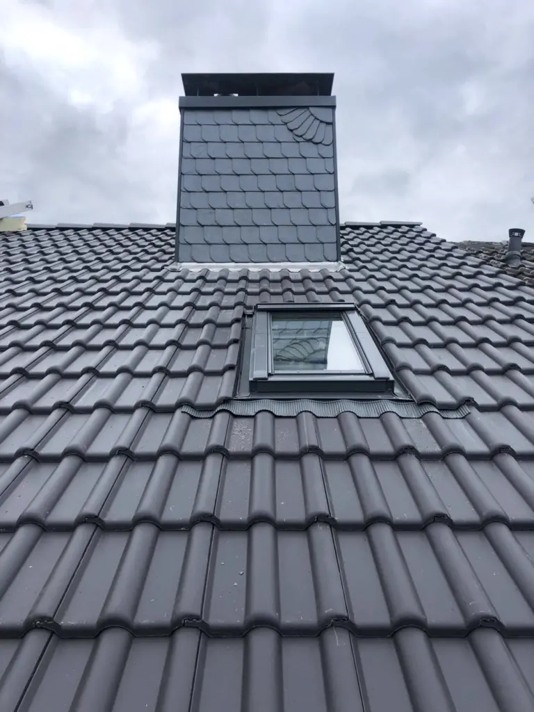 Neu eingebautes Dachfenster in einem dunklen Ziegeldach